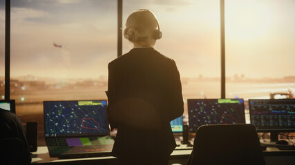 Female Air Traffic Controller with Headset Talk on a Call in Airport Tower. Office Room is Full of Desktop Computer Displays with Navigation Screens, Airplane Flight Radar Data for the Team. © Gorodenkoff