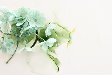 Creative image of pastel mint green Hydrangea flowers on artistic ink background. Top view with copy space