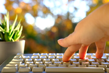 closeup female hands of elderly woman typing text on computer keyboard in garden, concept of learning to use computer at any age, modern technology, working, learning from home