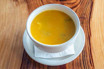 Natural pumpkin, butternut pumpkin soup in a white bowl. On a wooden background. Close up. View from above.