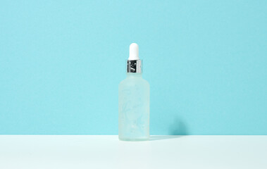white glass bottle with pipette stands on a blue background. Cosmetics SPA branding. Packaging for gel, serum, advertising and product promotion, mock up