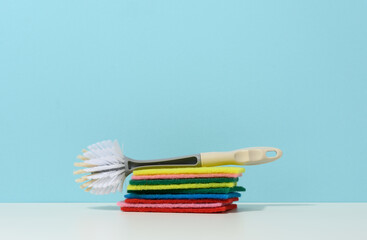 sponge and plastic brush with handle for cleaning the house on a blue background