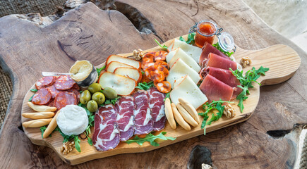 Very colorful tapas board of charcuterie with cheese and smoked meats. Decorated with arugula and...