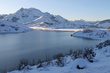 Obraz premium A winter image of a sunset on the banks of the Riaño reservoir in the Cantabrian mountains, León, Spain