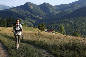 Fototapeta premium Tourist with backpack and trekking poles hiking through mountains, space for text