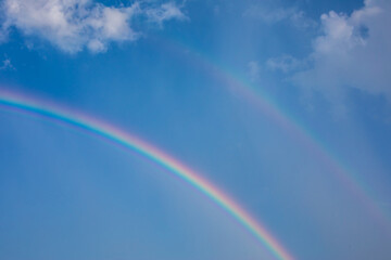 Beautiful rainbow with blue sky and clouds.