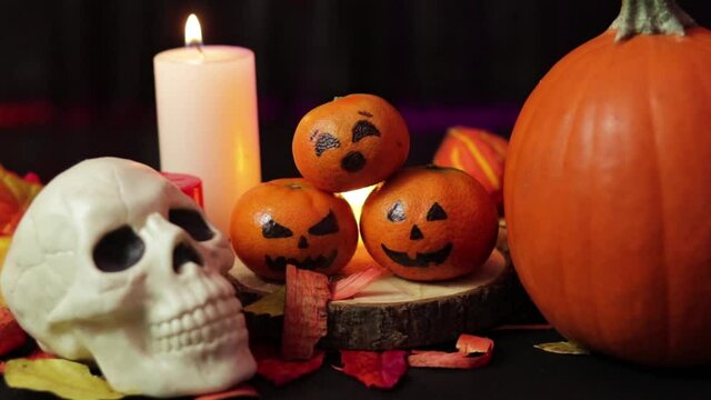 Halloween and autumn decorations. Skull, candle, tangerine, pumpkin and smoke.