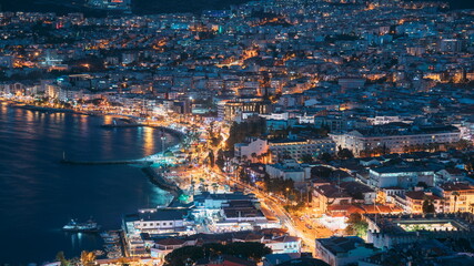 Kusadasi, Aydin Province, Turkey. Waterfront And Kusadasi Cityscape In Summer Evening. Night Scenic View Of Kusadasi Skyline At Aegean Coast, Turkey. 4K