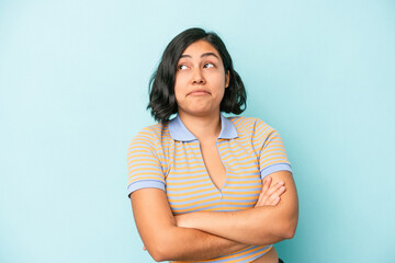 Young latin woman isolated on blue background dreaming of achieving goals and purposes