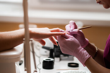 Fine brush manicure nail polish, nail polish, modeling gel. A woman gets a manicure in the salon.