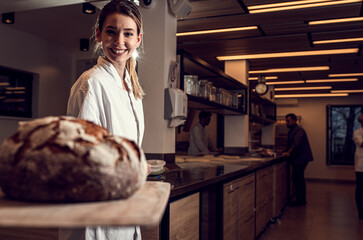 Female baker bakes bread in modern manufacturing.