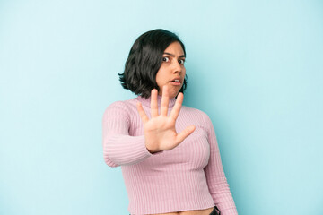 Young latin woman isolated on blue background being shocked due to an imminent danger