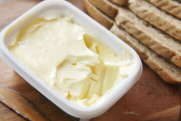 salted butter in a plastic container and breads on table 