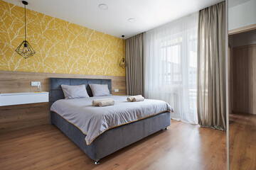 Fototapeta na wymiar a bed with a soft headboard in a Scandinavian-style bedroom in yellow tones