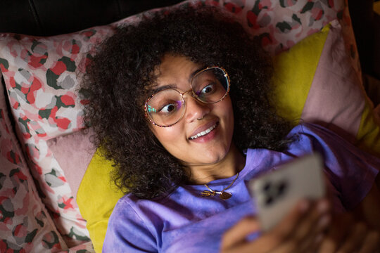 Overhead shot of young adult female looking surprised at a smartphone