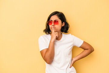 Young latin woman isolated on yellow background keeping a secret or asking for silence.