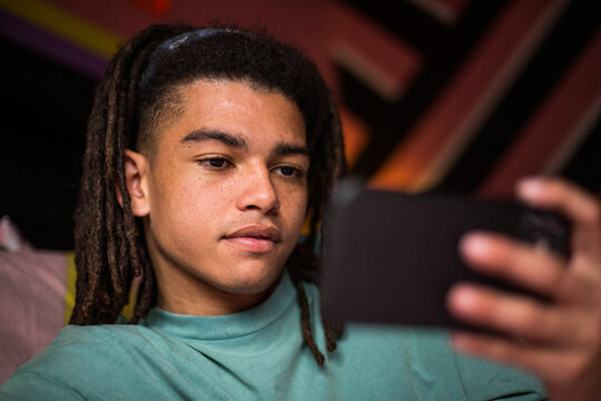 Gen Z male holding a smartphone at home