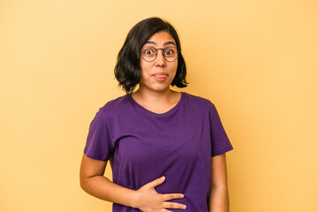 Obraz premium Young latin woman isolated on yellow background touches tummy, smiles gently, eating and satisfaction concept.