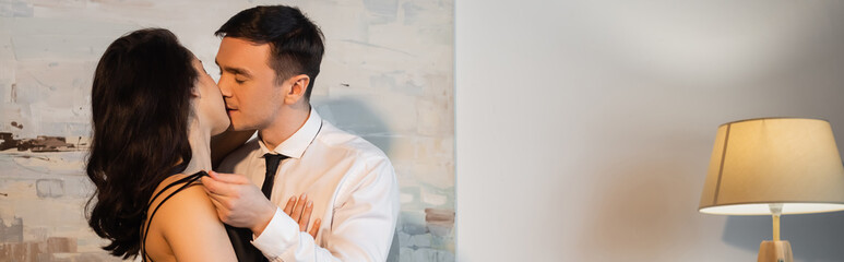 man in suit touching straps on slip dress and kissing sexy woman, banner