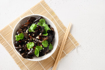 Salad of pickled tree black muer mushrooms in bowl on white background. View from above. Copy space. Chinese cuisine.