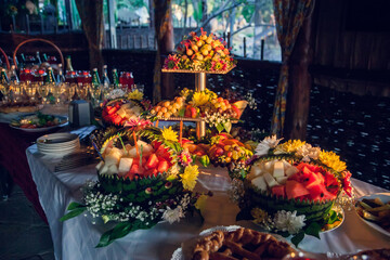 Fruit table with Canape appetizer: carved watermelons filled with pieces of melon and watermelon pulp, decorated with fresh flowers