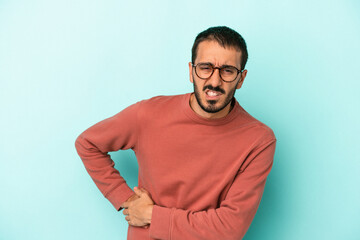 Young caucasian man isolated on blue background having a liver pain, stomach ache.