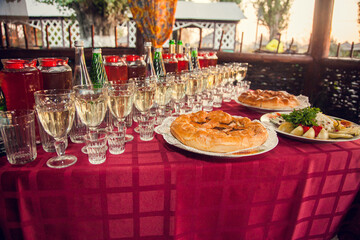 Russian feast. Table set with Russian snacks: pies with stuffing, pickles, drinks poured into glasses