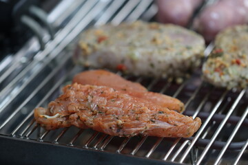 Churrasqueira elétrica com carnes sobre grelha, linguiça, frango e pernil de porco