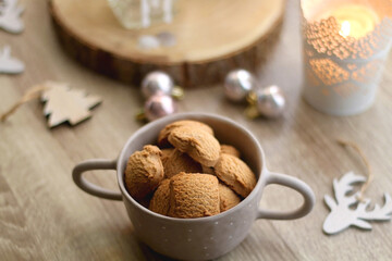 Bowl of cinnamon cookies, lit candles and various Christmas decorations on the table. Selective focus.
