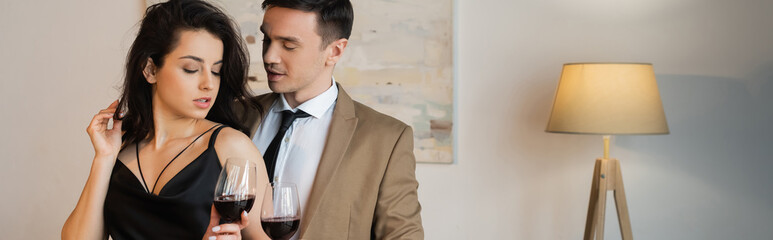 young sexy couple holding glasses of red wine, banner