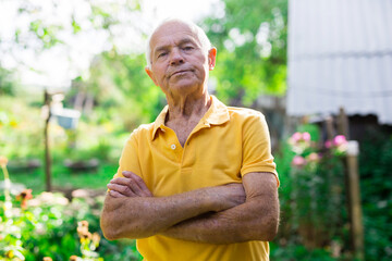 Portrait of an elderly man 70 years old in his garden on summer sunny day