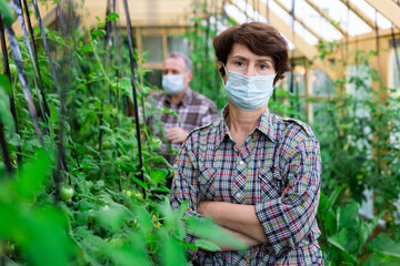 Portrait of mature woman in protective mask in greenhouse