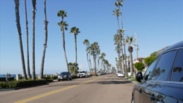 Defocused road with palm trees in California, Oceanside tropical beach resort, USA. Waterfront street near pacific ocean. American summertime, Los Angeles Hollywood aesthetic. Yellow dividing line.