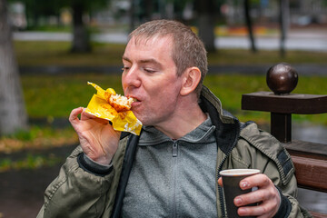 Man in the park sitting on a bench enjoying a sweet and delicious cupcake