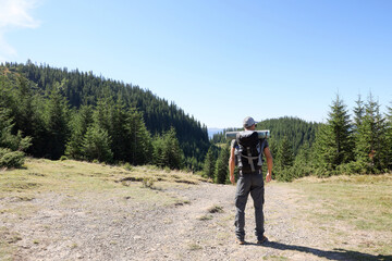 Fototapeta na wymiar Tourist with backpack in mountains on sunny day, back view. Space for text