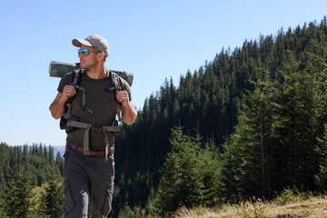 Tourist with backpack in mountains on sunny day. Space for text