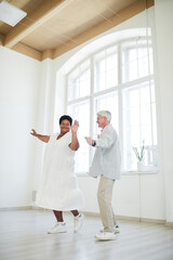 Happy African woman dancing together with senior man during dance lesson in studio