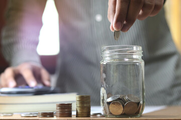 businessman holding coins putting in glass. concept saving money for finance accounting.