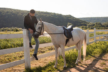 The man is resting with a horse on a ranch