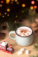 Hot chocolate with marshmallow, Christmas traditional cocoa drink on bokeh of lights. Festive winter atmosphere