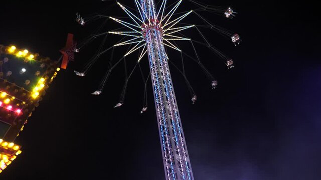 Tower Swinger Ride In Amusement Park at night at anual funfair