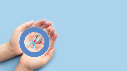 World diabetes day awareness concept. Hands holding blue ribbon with blood drop and blue circle of...