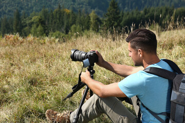 Man taking photo of nature with modern camera on tripod outdoors