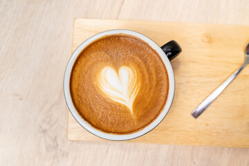 Latte coffee or cappuccino coffee in black cup with beautiful heart latte art on wooden table., Top view of latte coffee
