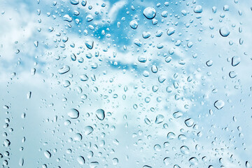Rain drop on window glass with blue sky and cloud background