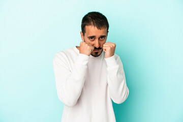 Young caucasian man isolated on blue background throwing a punch, anger, fighting due to an argument, boxing.