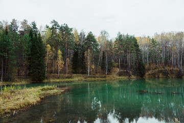 Fototapeta na wymiar Autumn lake in the middle of forest. Rustic autumn landscape.