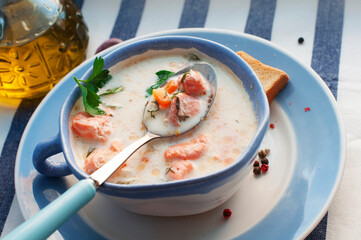 Creamy salmon soup Kalakeitto with salmon, carrot, parsley, onion, garlic, potatoes, croutons and spoon on white background. Traditional Finnish hot soup