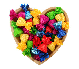 Heart shaped plate with candies in colorful wrappers isolated on white, top view