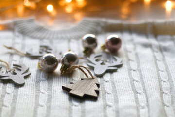 White cable knit sweater and various Christmas decorations on wooden background. Selective focus.